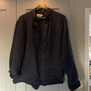 Mörkblå linneskjorta i storlek S - Mörkblå linneskjorta från Cubus, otroligt passande nu till det varmare vädret och den är sparsamt använd utan defekter. Nypris ligger på 600kr