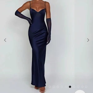 Balklänning - Elegant mörkblå långklänning med smala axelband och en figurnära passform. Klänningen har en v-ringad design och är tillverkad i ett glansigt material som ger en lyxig känsla. Perfekt för festliga tillfällen. Passar till balen och är köpt för ungefär 1700kr med frakt och till från Babyboo. Endast testad och går till fötterna på mig som är 168cm💙