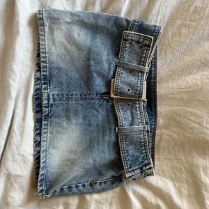 Denimkjol mini - Mini jeanskjol med bälte från Monki. Helt oanvänd och passar bra till lika bra till vardags som till en festival outfit. Perfekt längd och man behöver inte oroa sig att den ska åka upp