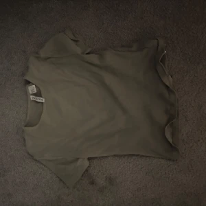 Grå ribbad t-shirt från Divided - Säljer en stilren grå ribbad t-shirt från Divided. Perfekt för en avslappnad look. T-shirten har korta ärmar och en perfekt passform!