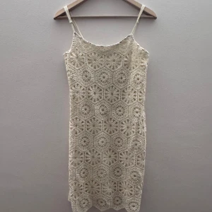 Beige virkad klänning - Säljer en snygg beige virkad klänning med smala axelband. Klänningen har ett unikt mönster och är perfekt för varma dagar. Den är både stilren och bekväm, vilket gör den till ett måste i garderoben. Passar perfekt för sommarens alla tillfällen! är helt ny har aldrig använt pris lapp fins!