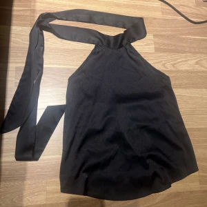 Svart oneshoulder topp - Snygg svart oneshoulder topp med knytband. Perfekt för en stilren look. Passar bra till både jeans och kjol.