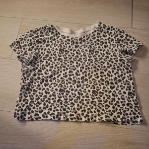 Leopardmönstrad kortärmad topp från H&M - Säljer en cool leopardmönstrad topp från H&M:s Divided-kollektion. Den är kortärmad och har en avslappnad passform, perfekt för en trendig look. 🐆 Lite kortare i modell. Pris kan diskuteras❤️