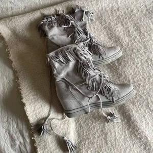 Grå mocka boots med fransar - Snygga grå boots i mocka med fransdetaljer och snörning. Perfekt Boho/stockholm touch nu till våren och sommaren! Finns fåtal spår av användning (syns på bilderna). ✨