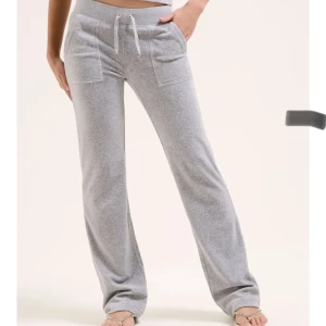 Juicy couture gråa - Snygga grå mjukisbyxor med snörning i midjan och praktiska fickor fram och bak. Byxorna har en bekväm passform och är perfekta för en avslappnad stil. De är tillverkade i ett mjukt material som ger en skön känsla hela dagen.