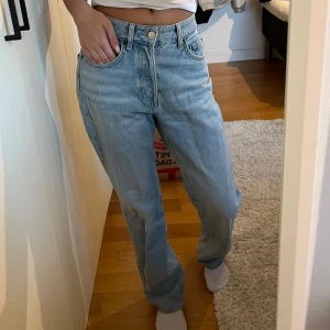 Ljusblå jeans från H&M - Snygga ljusblå jeans från H&M med en klassisk femficksdesign och knappgylf. De har en rak passform och är perfekta för en avslappnad stil. Jeansen är tillverkade i ett bekvämt denimtyg som ger en skön känsla hela dagen.