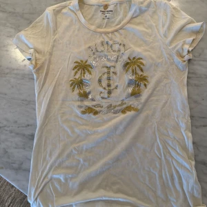 Vit t-shirt från Juicy Couture - Vit Juicy Couture t-shirt med tryck i guld och silver. Passar även storlek S.