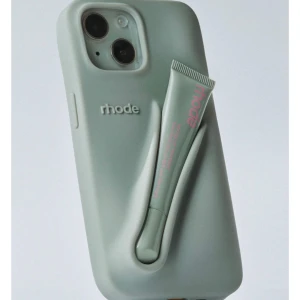 Rhode Iphone Case+Peptide liptint  - Säljer ett Rhode mobilskal för Iphone 15 pro plus, passar för de andra pro plus telefonerna också. Har även tillhörande peptide lip tint som sitter i skalet i färgen Toast. Texten på liptintet har blivit superlite slitet pga användning när jag hållt i telefonen. Köpt från rhodes egna hemsida, fått hjälp med frakt från familjekompis i kanada. För mer egna bilder etc så skicka gärna pm! Säljer för 700kr plus frakt