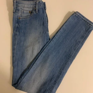 Blå skinny jeans - Snygga blå skinny jeans med regular waist. Klassisk femficksdesign och dragkedja med knapp framtill. Perfekta för en stilren look.