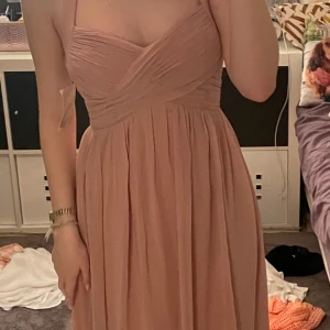 Balklänning / långklänning ljusrosa  - Elegant rosa långklänning med omlott-design och smala axelband. Perfekt för en speciell kväll med sin vackra passform och mjuka tyg. Klänningen har en subtil drapering över bysten som ger en fin detalj. Från chiara forthi milano, storlek S, aldrig använd, ny med prislapp, tror org pris var 899kr 