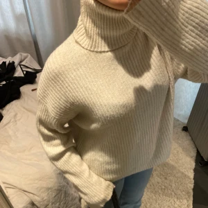 Beige stickad polotröja - Säljer en mysig beige stickad polotröja med ribbad design. Tröjan har långa ärmar och en hög polokrage som håller dig varm under kyliga dagar 🤎🤎