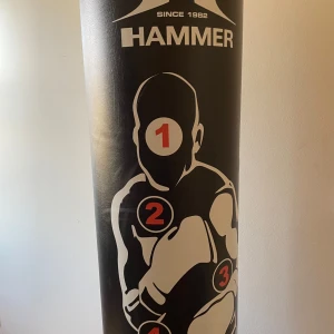 Svart boxningssäck från Hammer - Säljer en svart boxningssäck från Hammer med tryck av en silhuett och nummer för träning. Tillverkad i Italien, perfekt för boxningsträning hemma. Robust och hållbar design.