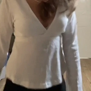 Vit v-ringad topp från Gina Tricot - Säljer en stilren vit v-ringad topp från Gina Tricot. Toppen har långa ärmar och en ribbad struktur som ger en snygg passform. Det är en tröja där man knyter där bak vilket gör att man kan justera hur tajt man vill ha den🤩😊💓