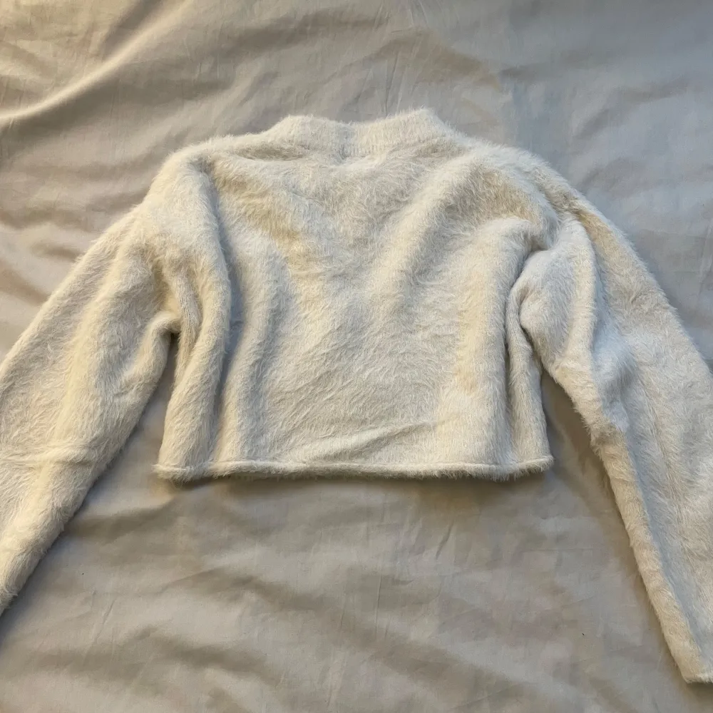 Säljer en supermjuk och fluffig vit croppad tröja från H&M. Perfekt för att hålla sig varm och stilren under kyliga dagar. Tröjan har långa ärmar och en hög krage som ger extra mysfaktor. Passar perfekt till jeans eller kjol för en trendig look.. Neuletakit & Villapaidat.