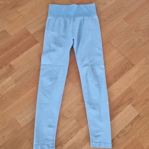 Ljusblå leggings - Säljer ett par ljusblå leggings med hög midja. Tillverkade av en mjuk och stretchig blandning av polyamid, polyester och elastan. Perfekta för en bekväm och stilren look.