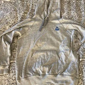 Grå hoodie från Isabel Marant - Säljer nu min älskade Isabel Marant hoodie, köpte den här från plick för cirka 1,5 år sedan och har använt den max 5 gånger kanske så därför väljer jag nu att sälja vidare! Den är så fin och passar till det mesta men den kommer bara inte till användning för mig! Den har en liten blå logga på bröstet 🩷