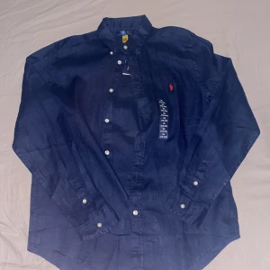 Ralph lauren linneskjorta - En helt ny mörkblå linneskjorta från ralph lauren nypris runt 1500 och säljer den för 899. Passar killar som är runt 175-180 skulle ja säga perfekt. Jag säljer den pgd av att jag råka beställa helt fel storlek och var alldedes för stor för mig. Om du har nån fråga om skjortan tveka inte att höra av dig