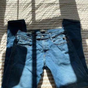 Blå jeans från Replay - Snygga blå jeans från Replay med klassisk femficksdesign och knappgylf. De har en modern passform och är perfekta för en avslappnad stil. Märkeslogga syns på bakfickan.