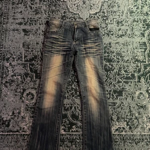 Lågmidjade Jeans - Snygga blå jeans med coola slitningar och nitar vid fickorna. En bekväm passform. Perfekta för en avslappnad stil med en touch av edge. Säljer då de var lite korta för mig. Midjemått- 36 mätt rakt över, innerbenslängd- 75cm💕 hör av er vid frågor och funderingar😊