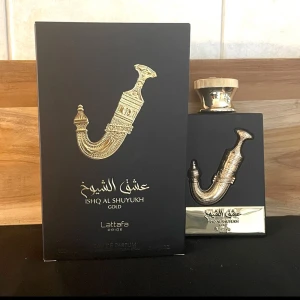Ishq Al Shuyukh Gold Parfym från Lattafa - Elegant parfymflaska formad som en traditionell dolk, med gulddetaljer och en svart bas. Förpackningen är svart med gyllene arabiska inskriptioner. En lyxig doftupplevelse från Lattafa. 100ml flaska 90ml kvar! 