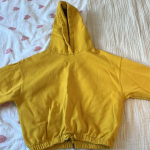 Gul hoodie från Zara - Säljer en gul magtröjshoodie från Zara i storlek 164. Den har en justerbar dragsko i nederkanten och en klassisk huva.