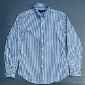 Ralph lauren skjorta - Säljer en skjorta från Ralph Lauren i slim fit. En schysst blå randig färg som är najs inför vår och sommar. Använd endast 2 gånger. Skriv vid minsta fundering!!