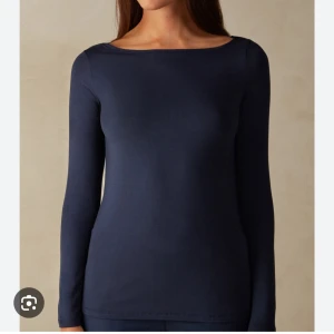 Mörkblå långärmad topp från Intimissimi - Säljer en stilren mörkblå långärmad topp från Intimissimi. Perfekt för en enkel och elegant look. Toppen har en rund hals och är tillverkad i ett mjukt material som ger en skön passform.