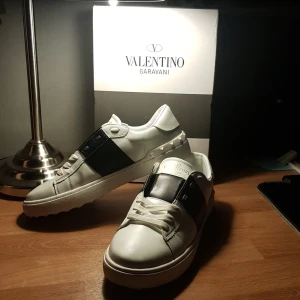 Valentino Garavani sneakers - Snygga Valentino Garavani sneakers i vitt skinn med svarta detaljer. Skorna har en klassisk design med snörning och en bekväm sula. Perfekta för en stilren look. Stl 41 jag säljer dessa skor pga av att jag har tröttnat på dom då jag har köpt andra skor och jag tänkte att dom kunde få ett nytt liv. Kan va intressant med byte.