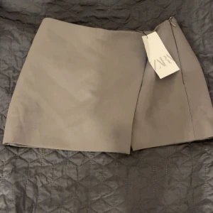 Grå kortkjol från Zara - Grå kort shortskjol från Zara.❣️Aldirg använd säljer för den inte passar 
