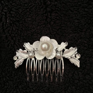 Silverfärgad hårkam med pärlor - Elegant silverfärgad hårkam dekorerad med blommor och pärlor. Perfekt för att ge en extra touch av glamour till din frisyr. Kammen har detaljerade blad och blommor med små pärlor i mitten.