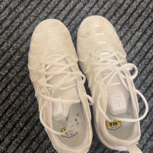 Vita Nike sneakers - Säljer ett par stilrena vita Nike sneakers med snörning och en unik sula. Perfekta för en sportig look och bekväma att bära hela dagen. Passar bra till både träning och vardag.