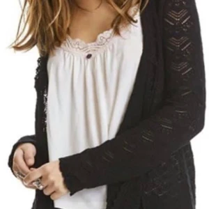Svart kofta från Odd Molly med snörning - Svart långärmad kofta från Odd Molly i stickat material med snyggt hålmönster och snörning framtill. Koftan har en feminin och bohemisk känsla med fina detaljer och passar perfekt till lager-på-lager-stil. Superenkel att matcha med olika outfits.