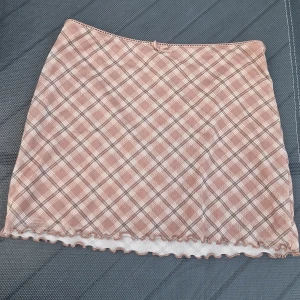 Vintage y2k miniskirt H&M Divided - Supersöt vintage y2k kortkjol i rutigt mönster från H&M Divided. Kjolen är i en beige-brun ton med vita och svarta rutor, har liten rosett upptill och vågig kant nertill. Brun innerkjol, ej genomskinlig. Y2k på hög nivå. Storlek XS.