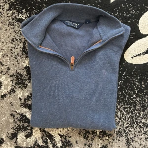1/4 zip polo ralph lauren golf - Snygg blå tröja från Polo Golf Ralph Lauren i storlek S. Tröjan har half zip med läderdetalj vid dragkedjan, hög krage och är tillverkad i mjuk bomull. Perfekt för lager-på-lager och chill stil. Långärmad och klassisk design.