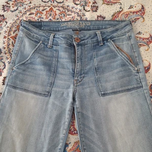 Ljusblå jeans från American Eagle - Ljusblå jeans från American Eagle med superstretch, stora framfickor och klassiska bakfickor med broderad detalj. Skador på fickor och fållar. 