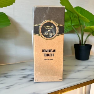 Dominican Tobacco Extrait de Parfum - Dominican Tobacco från Ibraheem Al Qurashi är en lyxig unisexparfym med tydliga noter av tobak, varm krydda, trä, lavendel och kanel. Flaskan är svart med gulddetaljer och har en elegant räfflad design. Innehåller 100 ml Extrait de Parfum.