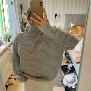 Ljusgrå stickad half zip tröja - Supermysig ljusgrå stickad tröja med half zip och hög krage. Oversized passform och långa ärmar, perfekt för lager på lager. Grovstickad struktur som ger en chill och trendig vibe.