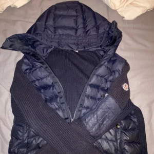 Mörkblå dunväst från Moncler - Snygg mörkblå dunväst från Moncler med huva och stickade detaljer på sidorna. Västen har dragkedja framtill och klassisk Moncler-logga på ärmen. Perfekt för lager-på-lager och ger en sportig vibe.             NFC scan ✅priset går att diskutera så hojta gärna till:)
