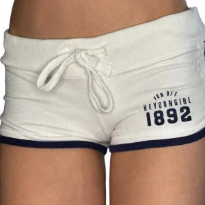 Vita shorts  - Superfräscha vita shorts med marinblå kant och tryck framtill. De har snörning i midjan. Inte så använda. Obs går ej ner i pris