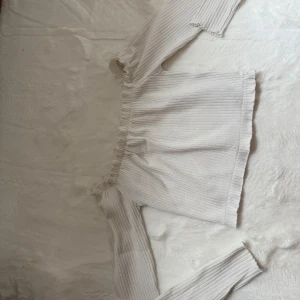 Vit offshoulder croppad topp - Superfin vit croppad topp med ribbat tyg och offshoulder-modell. Toppen har långa ärmar och smockad kant upptill och nedtill för en snygg passform. Från Nelly. Om du önskar fler bilder, skicka dm!🩷
