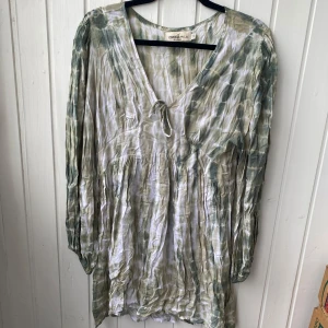 Grönvit klänning från Coconut Milk - Supersöt kortklänning i grönt och vitt från Coconut Milk by Stajl. Klänningen har v-ringning med knyt framtill, långa ärmar med resår vid handlederna och ett flowy, avslappnat fall. Är lite skrynklig men tror det är designen, annars inga defekter. Hör av er vid frågor!💕