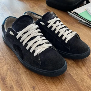 Oliver Cabell marinblå mockasneakers - Snygga marinblå sneakers från Oliver Cabell i mocka med vita snören och blå detalj på hälen. Skorna har en platt sula och rund tå, samt diskret logga på sidan. Perfekta för dig som gillar stilrena och klassiska sneakers med en twist. Du får med dig boxen till skorna. Priset går att diskuteras.
