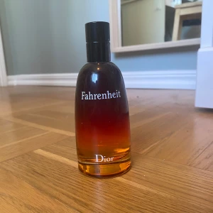 Dior Fahrenheit 100ml - Dior Fahrenheit After Shave Lotion i en snygg glasflaska med svart till orange gradient. Flaskan rymmer 100 ml och har en stilren design med tydlig logga. Perfekt för dig som gillar klassiska och maskulina dofter.