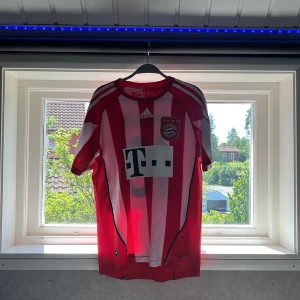 Bayern München Robben 10 Adidas tröja - Säljer en klassisk Bayern München matchtröja storlek S med Robben 10 på ryggen. Tröjan är röd och vit med breda ränder, Adidas-logga och Champions League-patchar på ärmarna. Tillverkad i lätt och ventilerande material, perfekt för fotboll eller samling. Kom med frågor!!