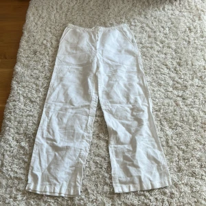 Vita linnebyxor från Kappahl stl 140 - Snygga och luftiga vita linnebyxor från Kappahl i storlek 140. Byxorna har resår i midjan och raka ben, perfekta för varma dagar. De har en enkel och clean look som passar till det mesta.