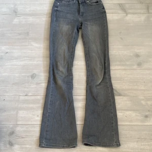Grå bootcut jeans från ONLY - Snygga grå jeans från ONLY i bootcut-modell. Jeansen har klassisk femficksdesign och är tillverkade i mjukt denimtyg. Perfekta för dig som gillar en retroinspirerad look med utsvängda ben.