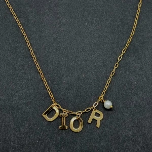 Guldhalsband Dior med pärldetalj - Snyggt handgjort halsband i guldtonad metall från Dior med kedja och hängande bokstäver som stavar DIOR. Längd-44cm