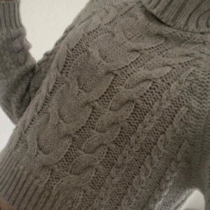 Grå stickad polotröja med flätmönster - Supermysig grå stickad polotröja!💕🤗 Tröjan har lång ärm och hög krage som ger en chill och trendig vibe. Perfekt för lager-på-lager och att hålla sig varm under kyliga dagar!🧣Stl: Xs  (se sista bild för en liten defekt på baksidan som knappast syns!)