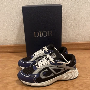 Dior B22 sneakers blå och svart. - Snygga Dior B30 sneakers i blått, svart och vitt med reflekterande detaljer och tydlig CD-logga på sidan. Skorna har vit snörning, chunky sula och meshpaneler för extra komfort. Perfekta för dig som vill sticka ut med exklusiv fin stil