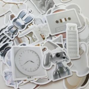 46st Estetiska Stickers: Silver & Vit Kollektion - En samling coola stickers med motiv som robotdjur, klockor, statyer, hörlurar, kassettband och pärlor. Perfekt för att dekorera laptops, mobilskal eller anteckningsböcker. Passar dig som gillar konst, retroprylar och modern estetik!